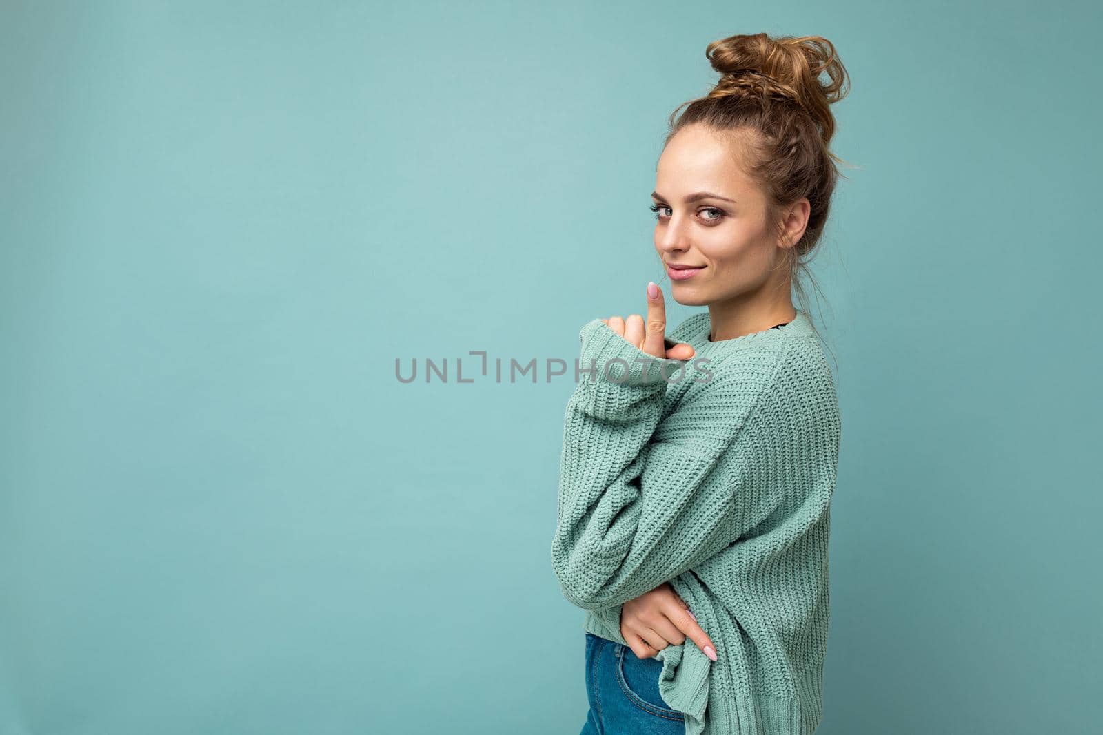 Portrait of young beautiful smiling hipster woman in trendy outfit. Sexy carefree female person posing isolated near blue wall in studio with free space. Positive model with natural makeup.