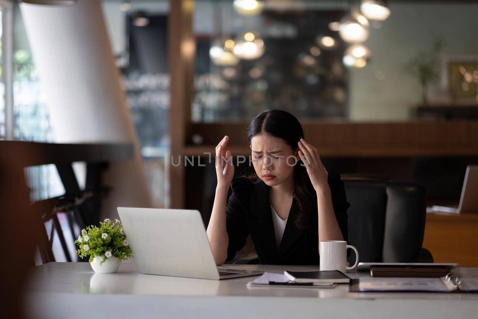 Stressed business woman working on laptop looking worried, tired and overwhelmed. asian female headache suffer from bad blurry weak vision tired of computer work syndrome, sight problem concept.