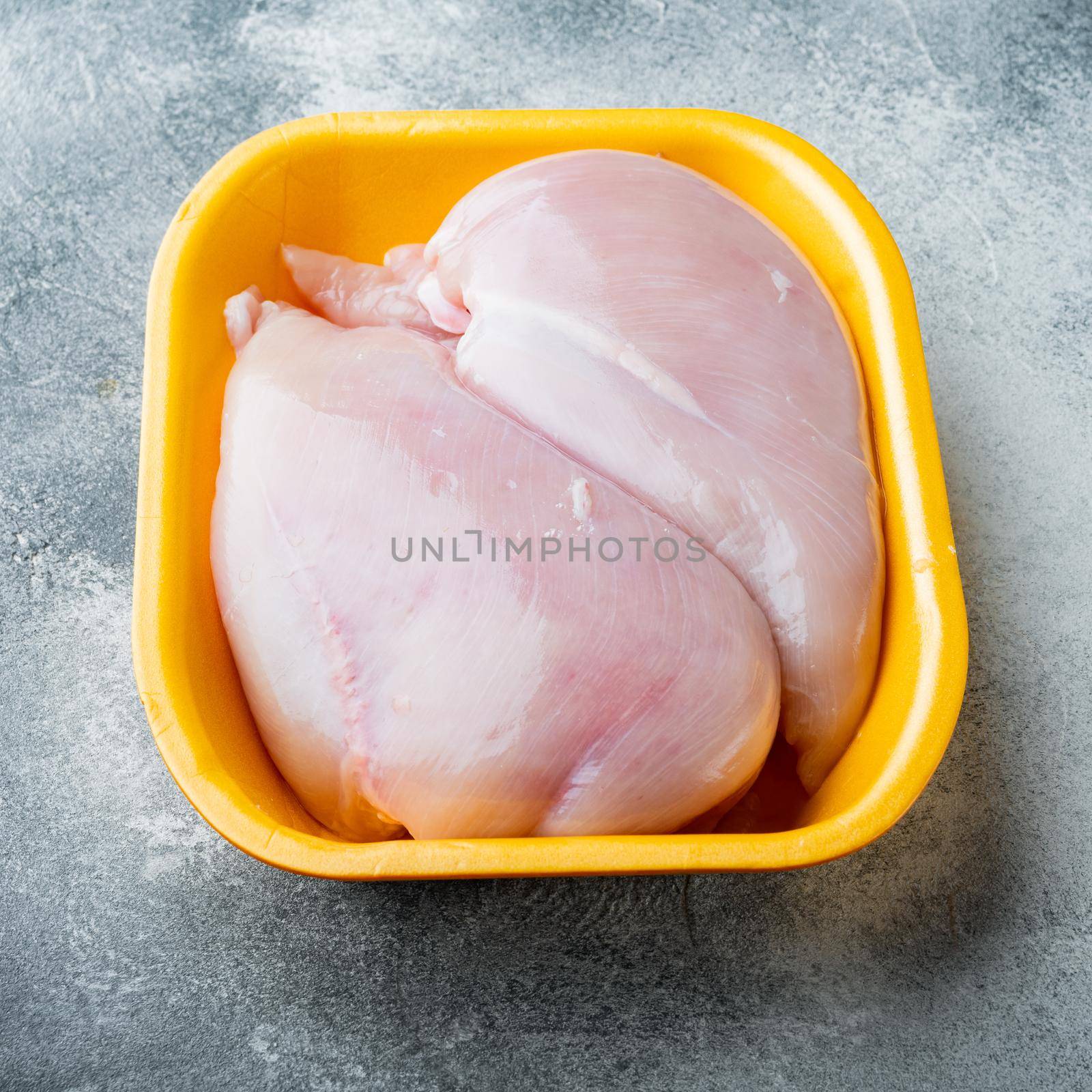 Raw chicken breast fillet in tray, on gray background by Ilianesolenyi