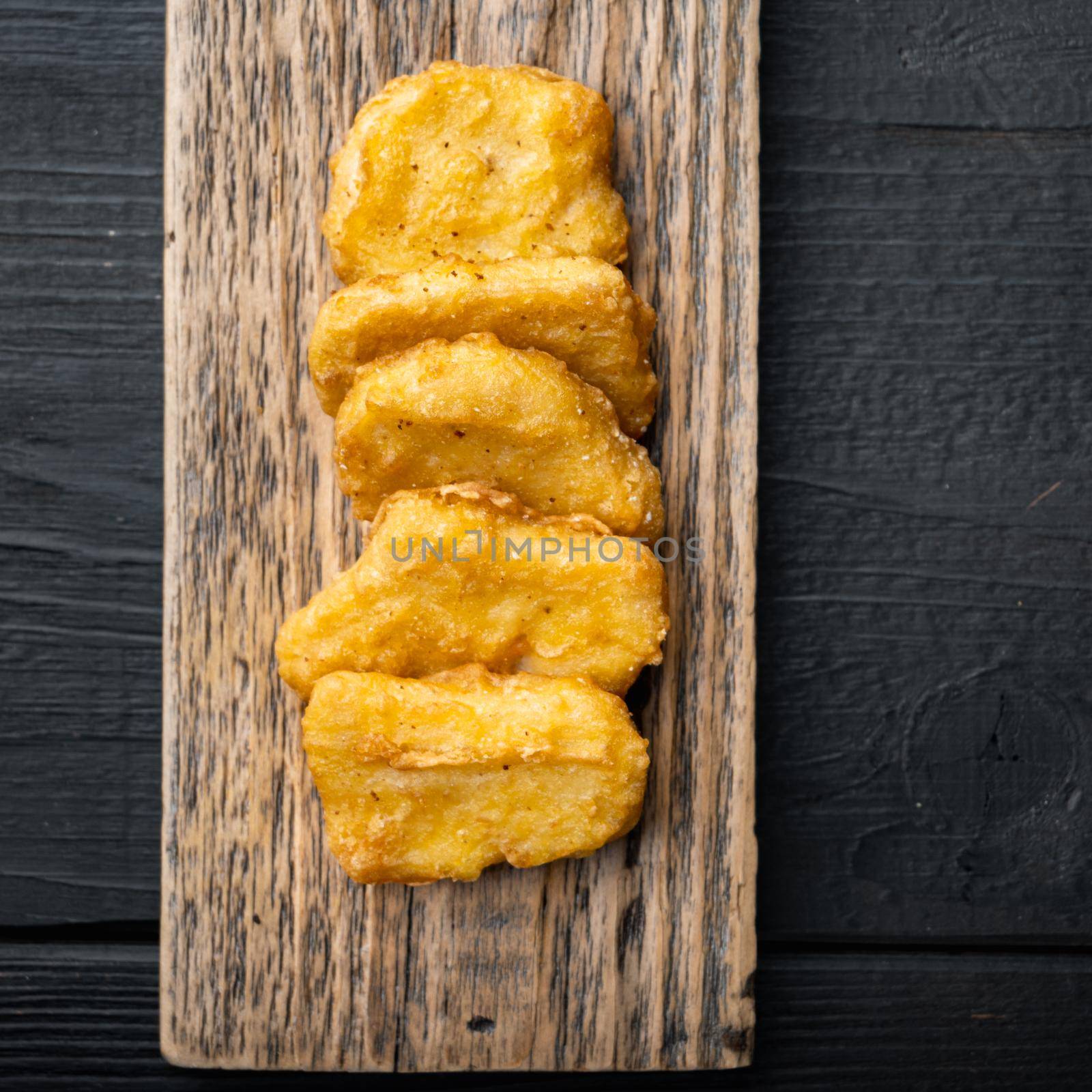 Homemade chicken nuggets fried on black wooden background, flat lay, with space for text.