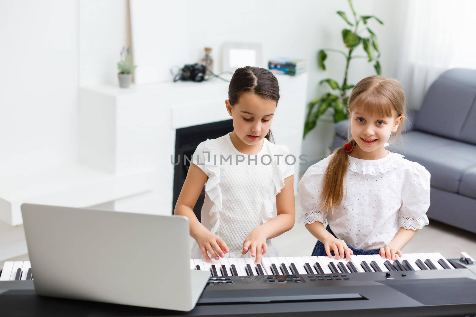 Home lesson on music for the girl on the piano. The idea of activities for the child at home during quarantine. Music concept by Andelov13