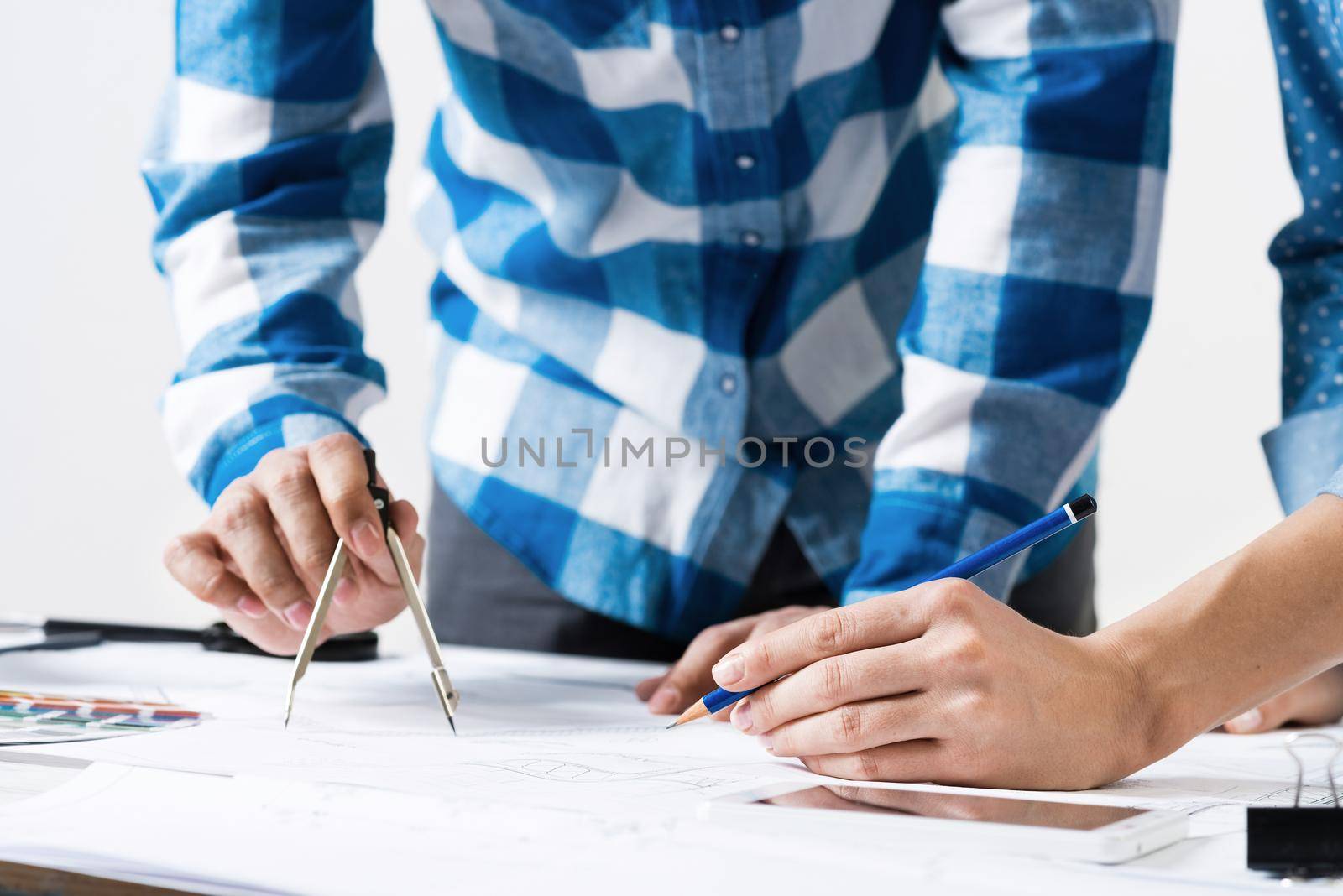 Professional designers discussing architecture project. Creative teamwork and project brainstorming. Close up human hands and construction drawing of building on desk. Industrial engineering company.