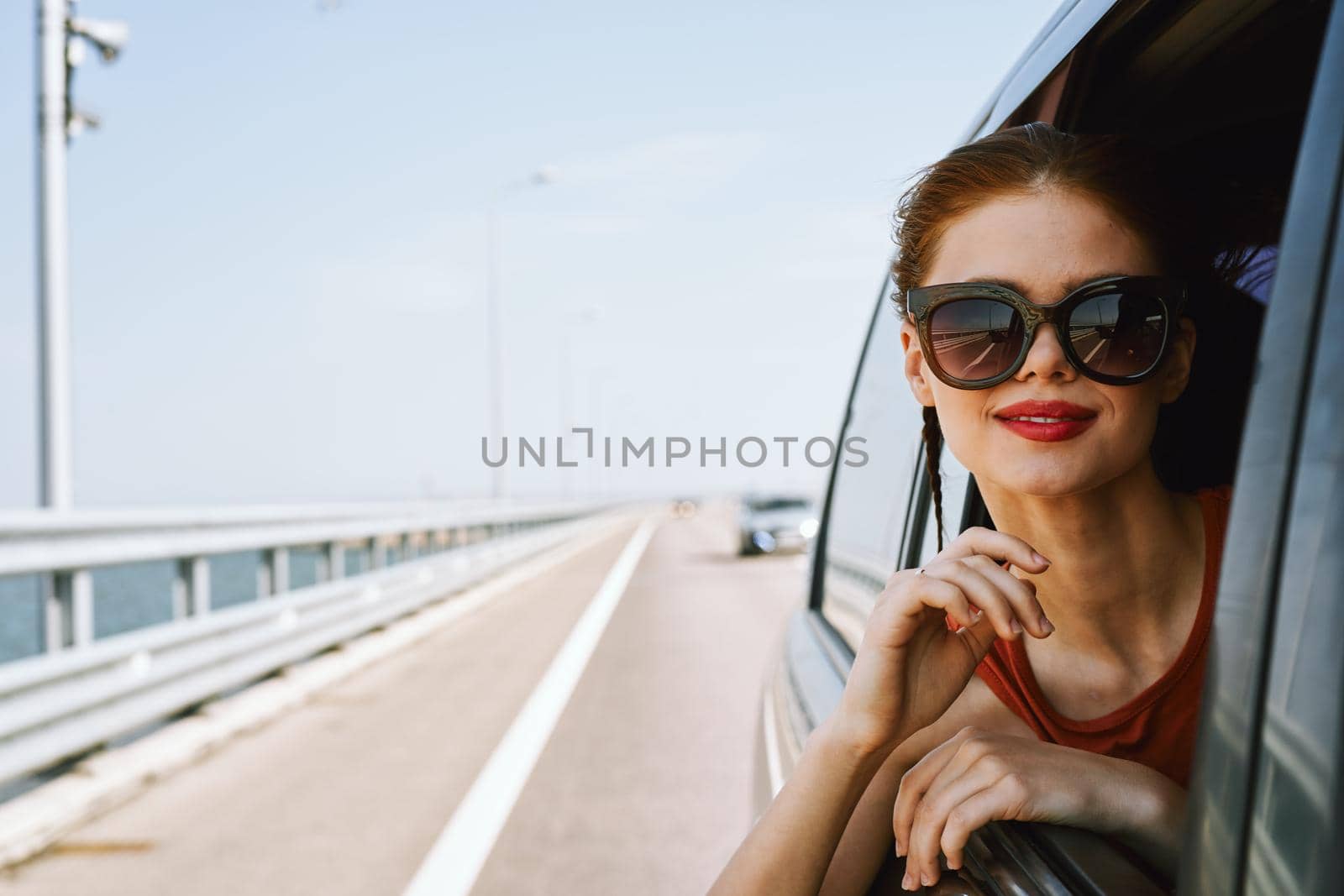 a woman is driving in a car on the road and looking out of the window. High quality photo