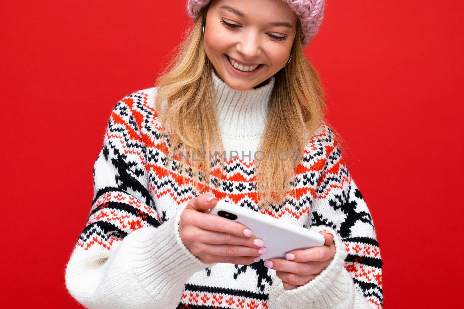 Young woman over isolated red background sending a message with the mobile.