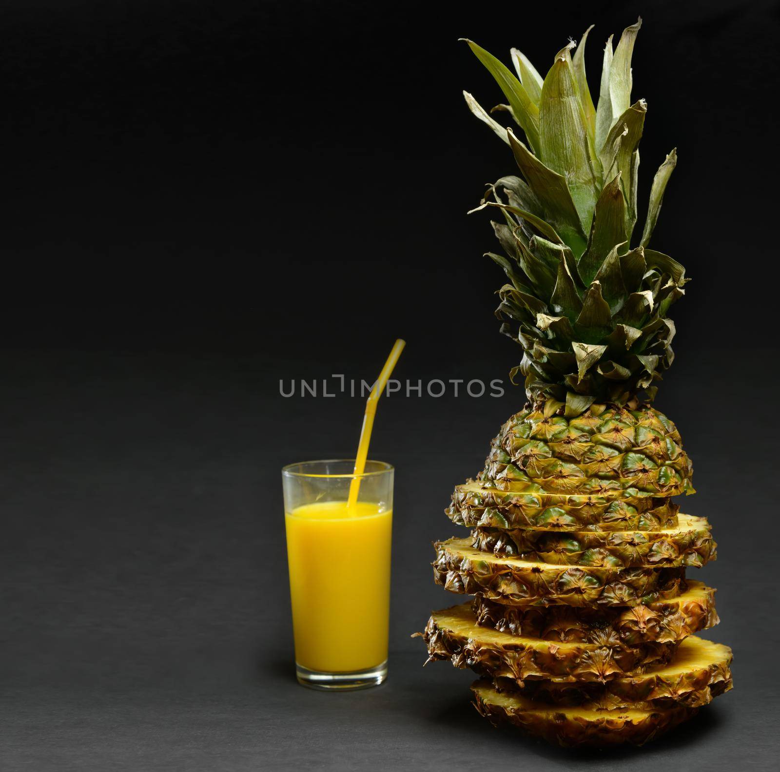 Delicious fresh pineapple juice and pineapple on a black background