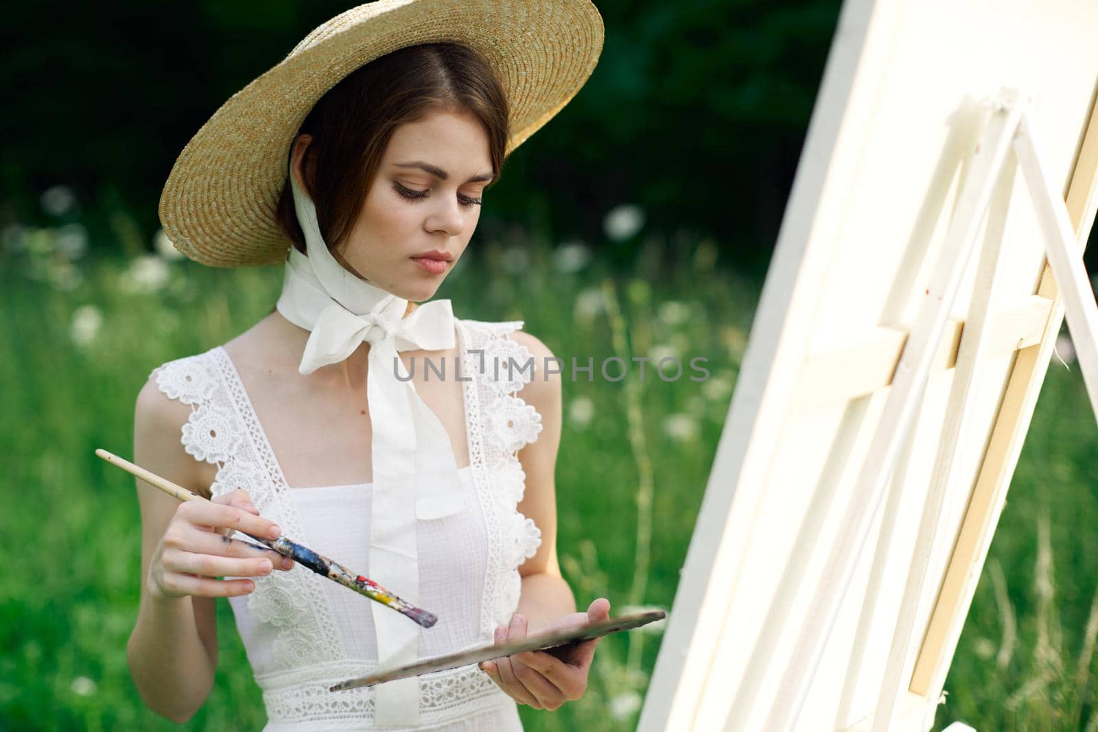 woman artist view with paint palette draws a picture in nature. High quality photo