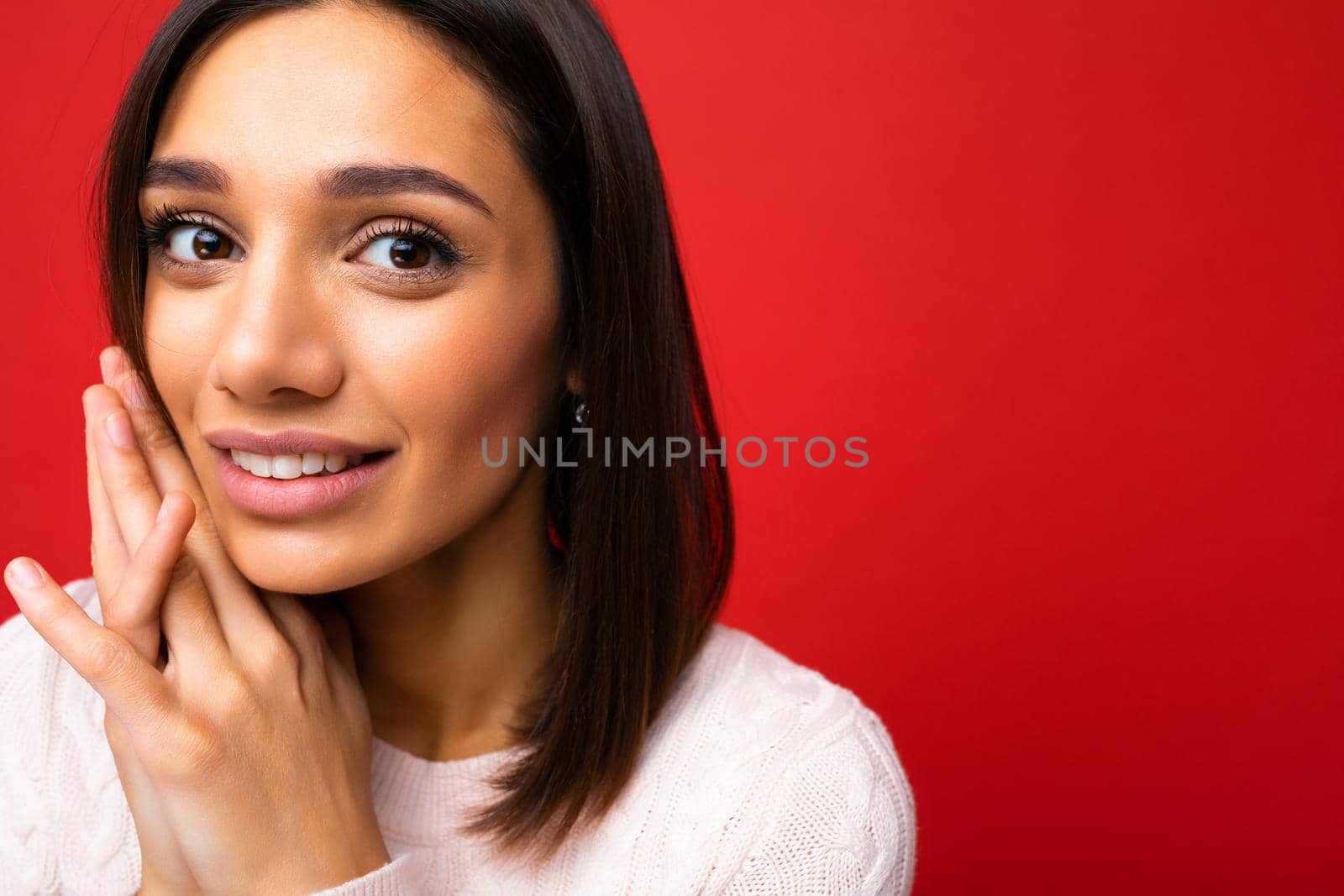 Closeup portrait of positive cheerful cute smiling young brunette woman in casual sweater isolated on red background with copy space.
