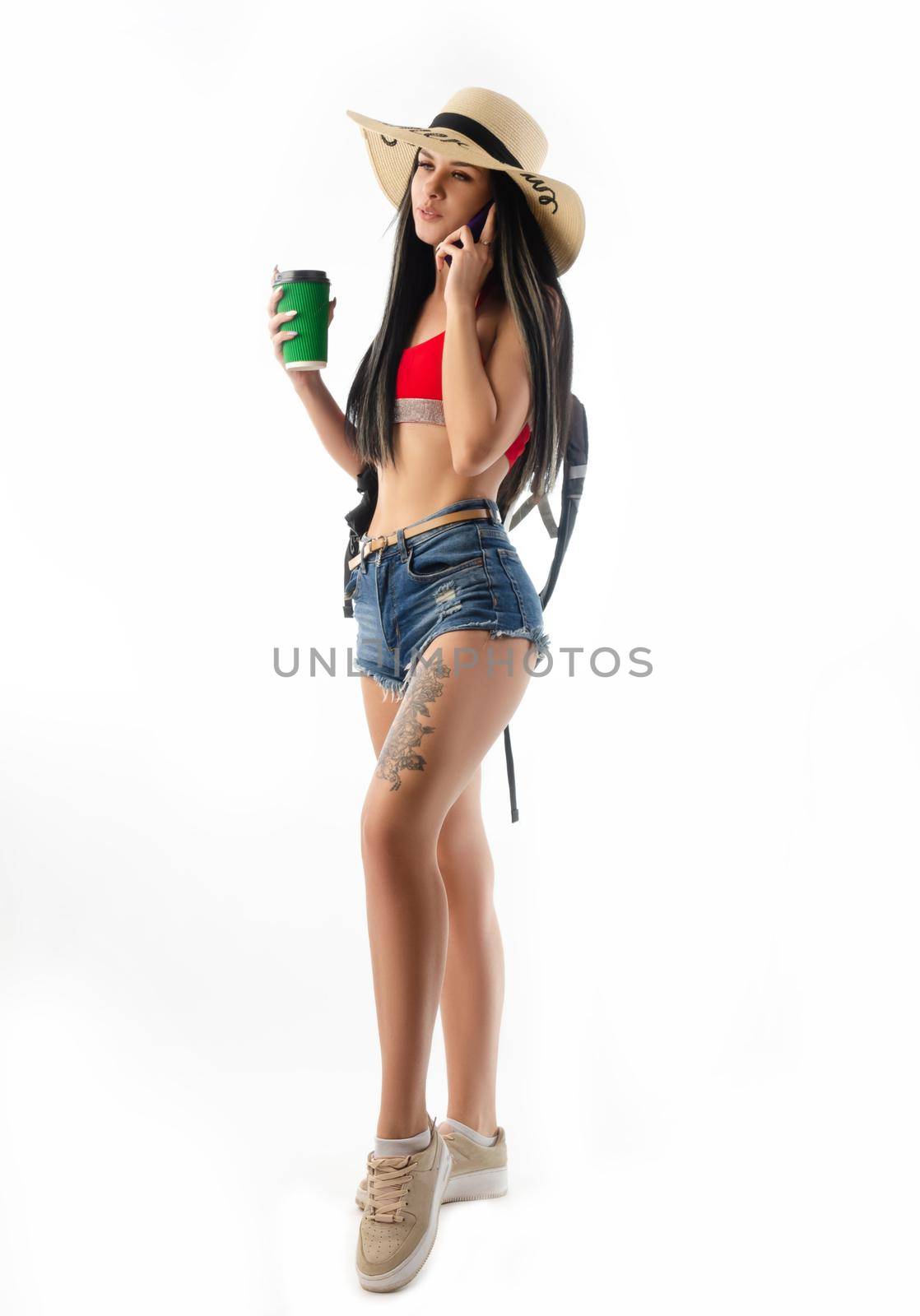 brunette in a hat in summer clothes slim and sexy with a phone isolated on a white background by Rotozey