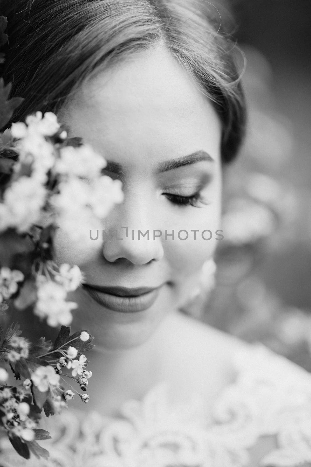 bride with a wedding bouquet in the forest near the bushes blooming with white flowers