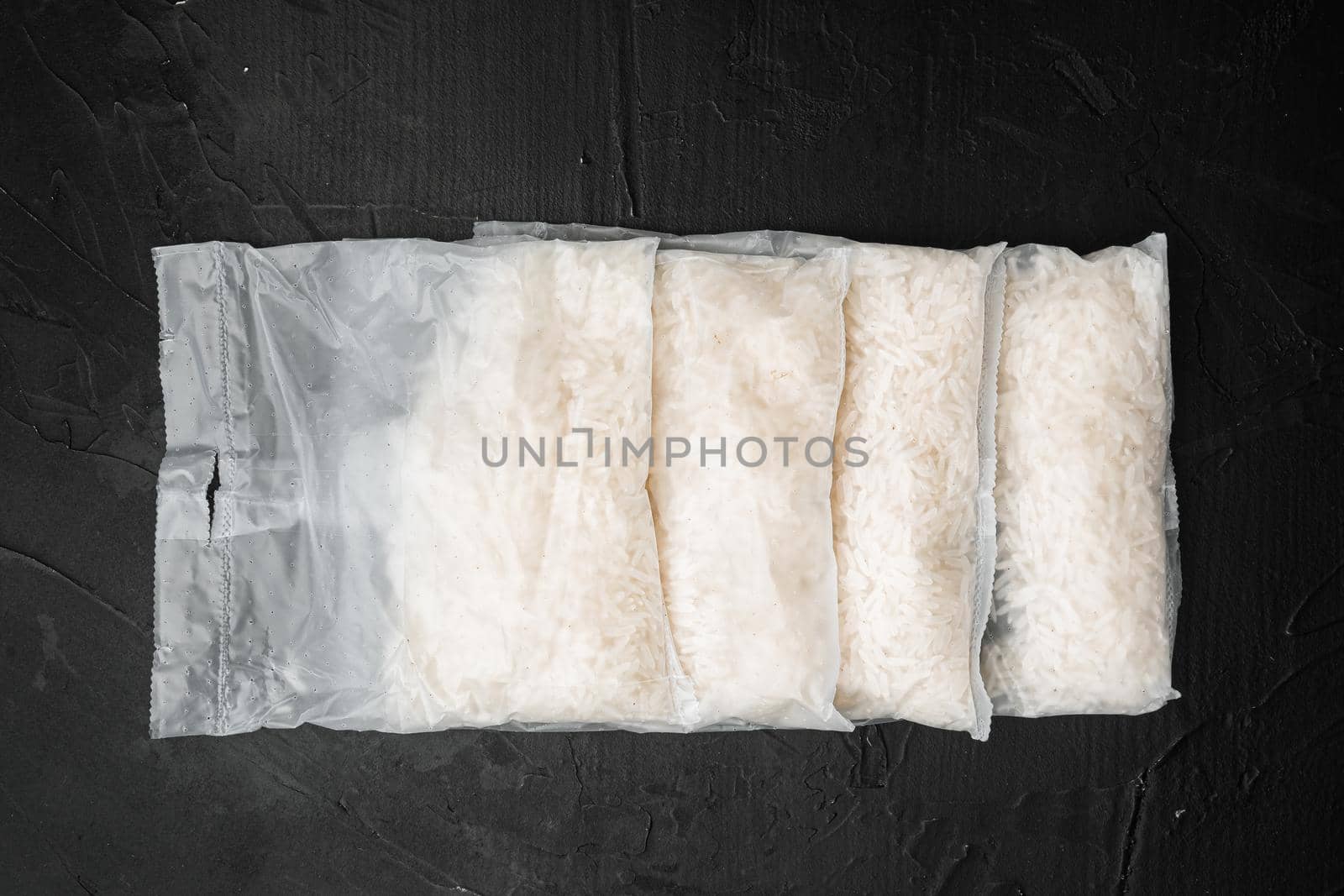 Rice in portion bags set, on black dark stone table background, top view flat lay
