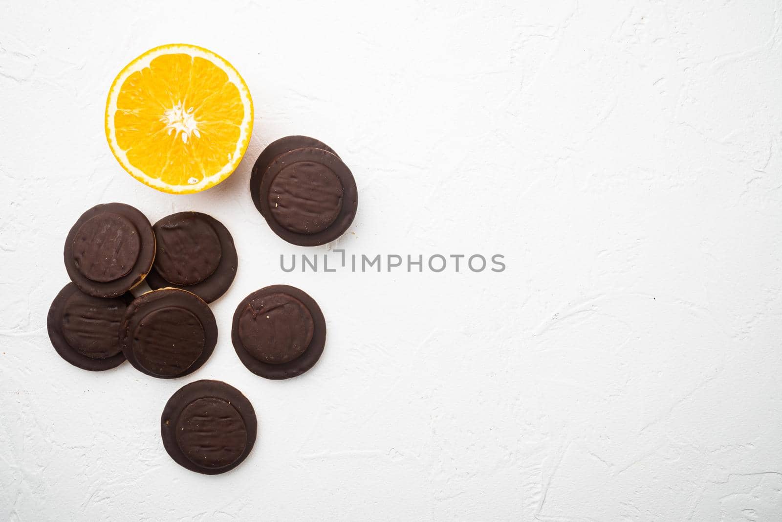 Jaffa Cakes. Cookies covered with dark chocolate and filled with orange marmalade set, on white stone table background, top view flat lay, with copy space for text