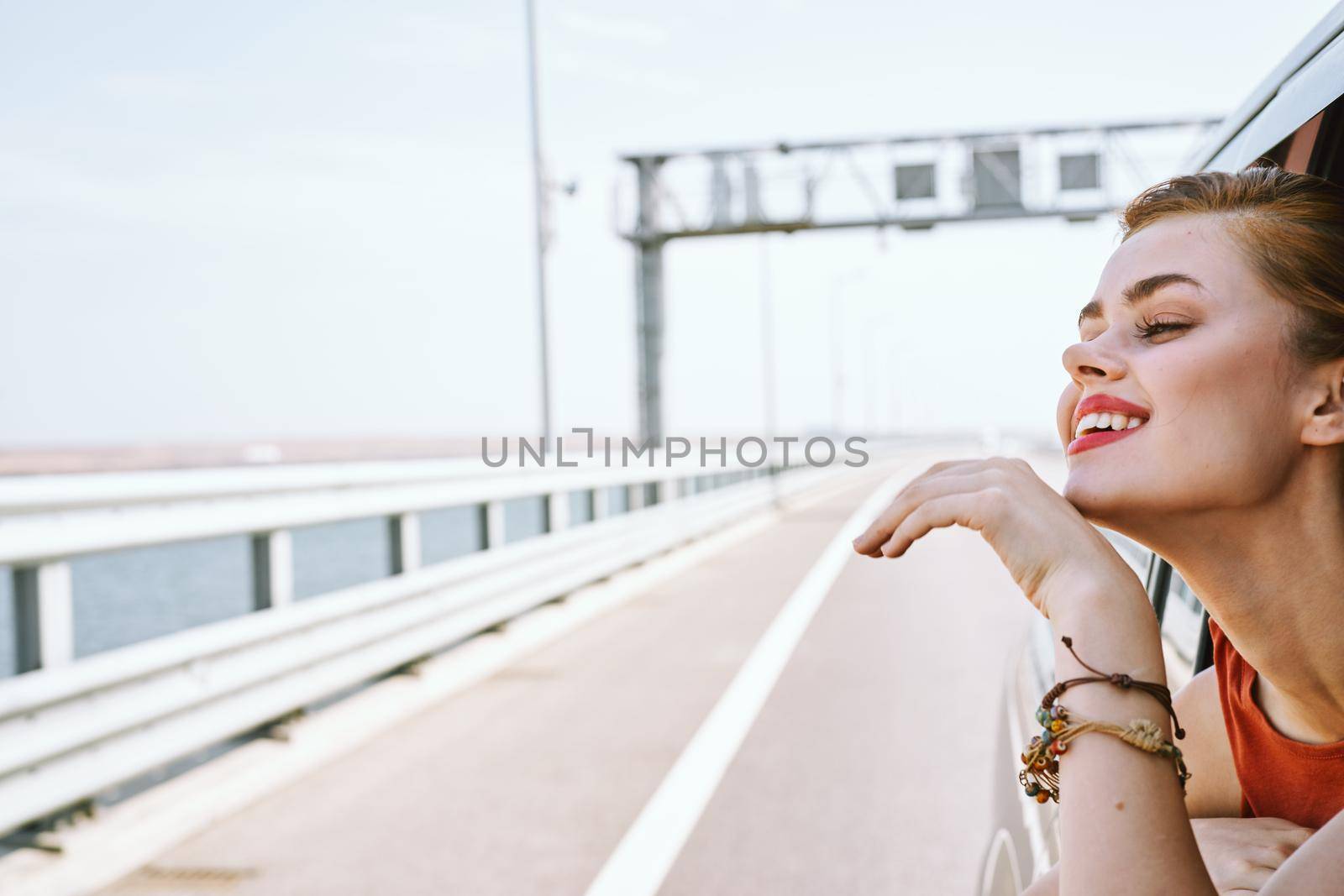 cheerful woman peeking out of the car window trip road travel by Vichizh