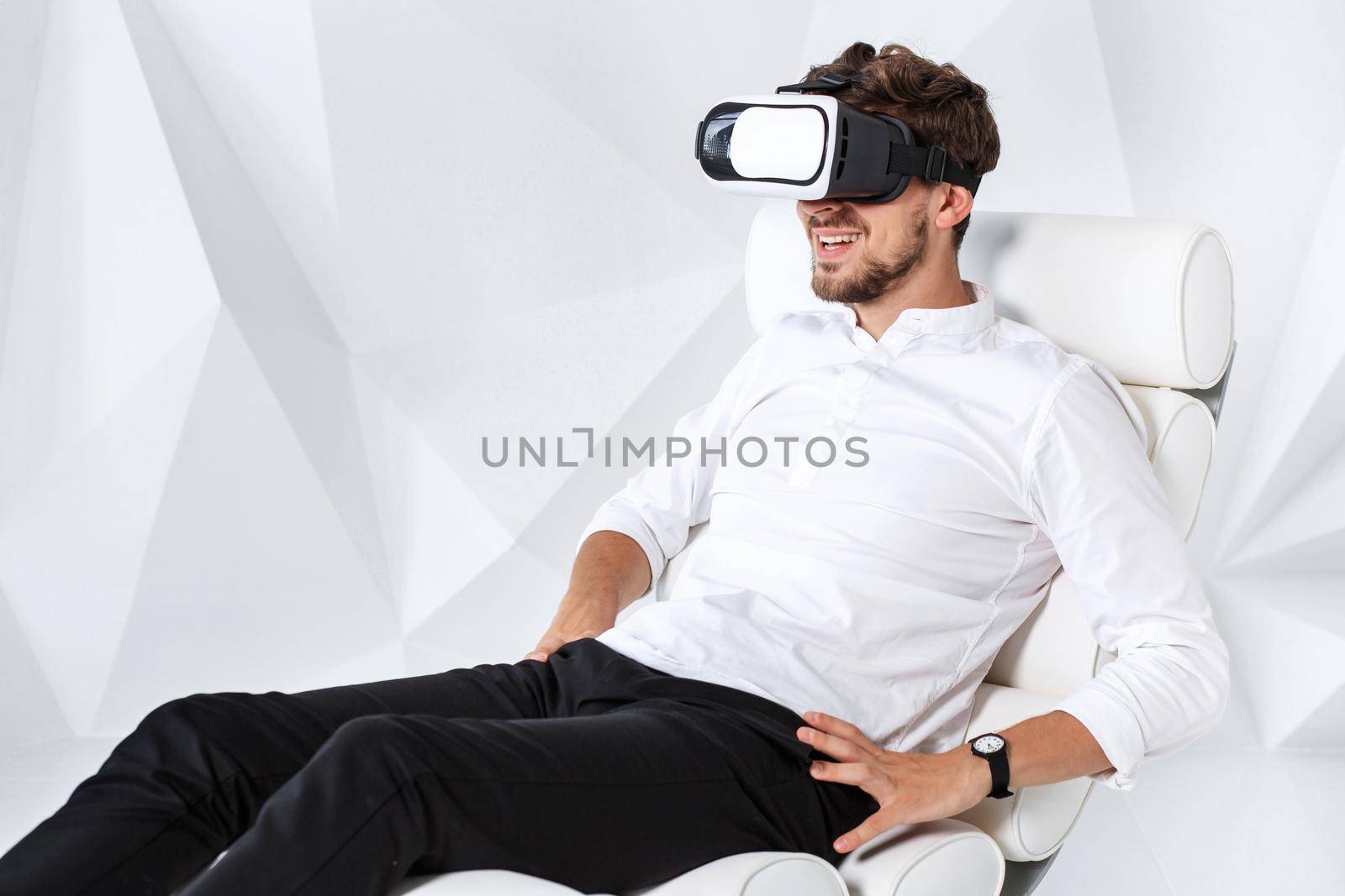 Excited young man is getting experience using VR-headset glasses of virtual reality gesticulating with his hands by nazarovsergey
