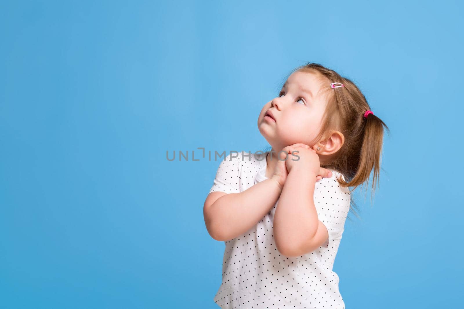 Funny kid in white T-shirt on blue background. Little pretty girl. Copy space for text. Sale, holidays, birthday party concept.