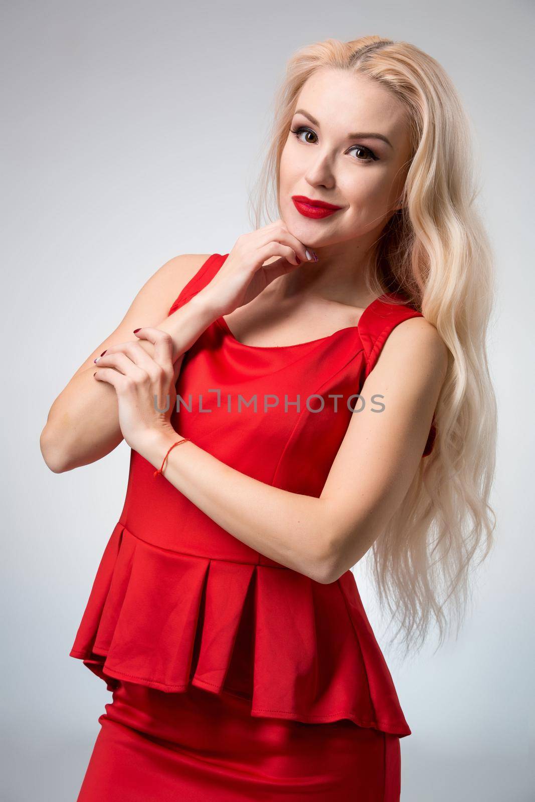 Glamorous young woman in red dress on gray background by nazarovsergey
