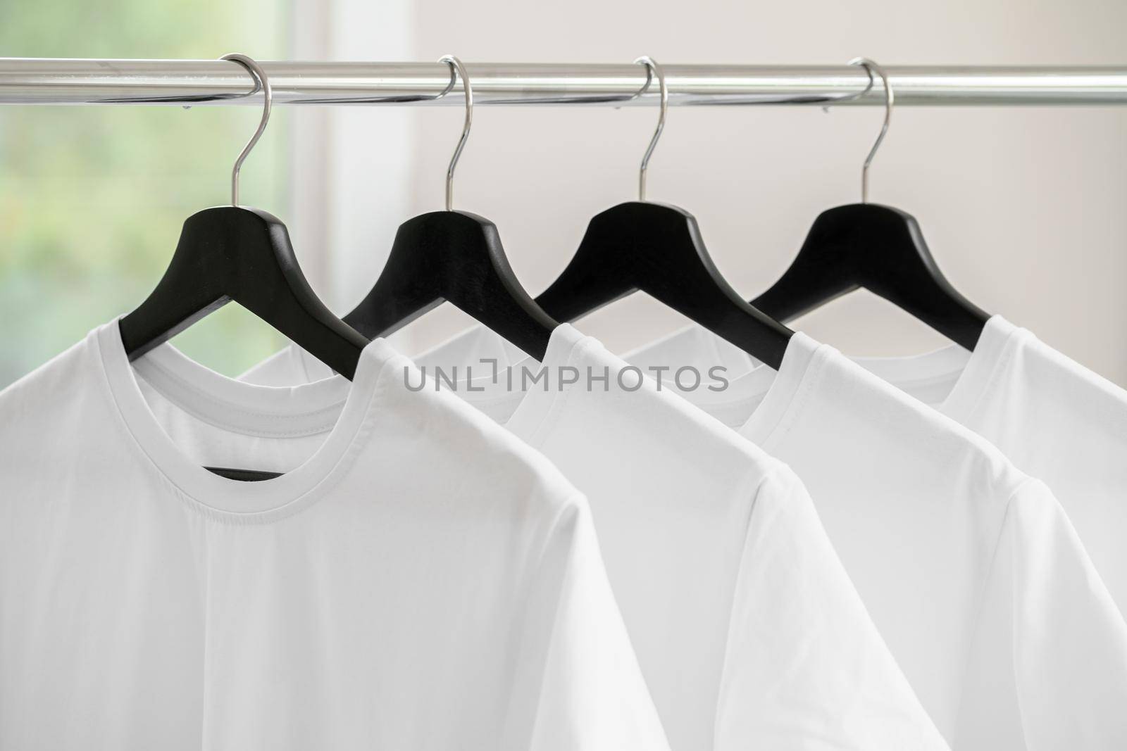Row of white t-shirts on hangers hanging on rack