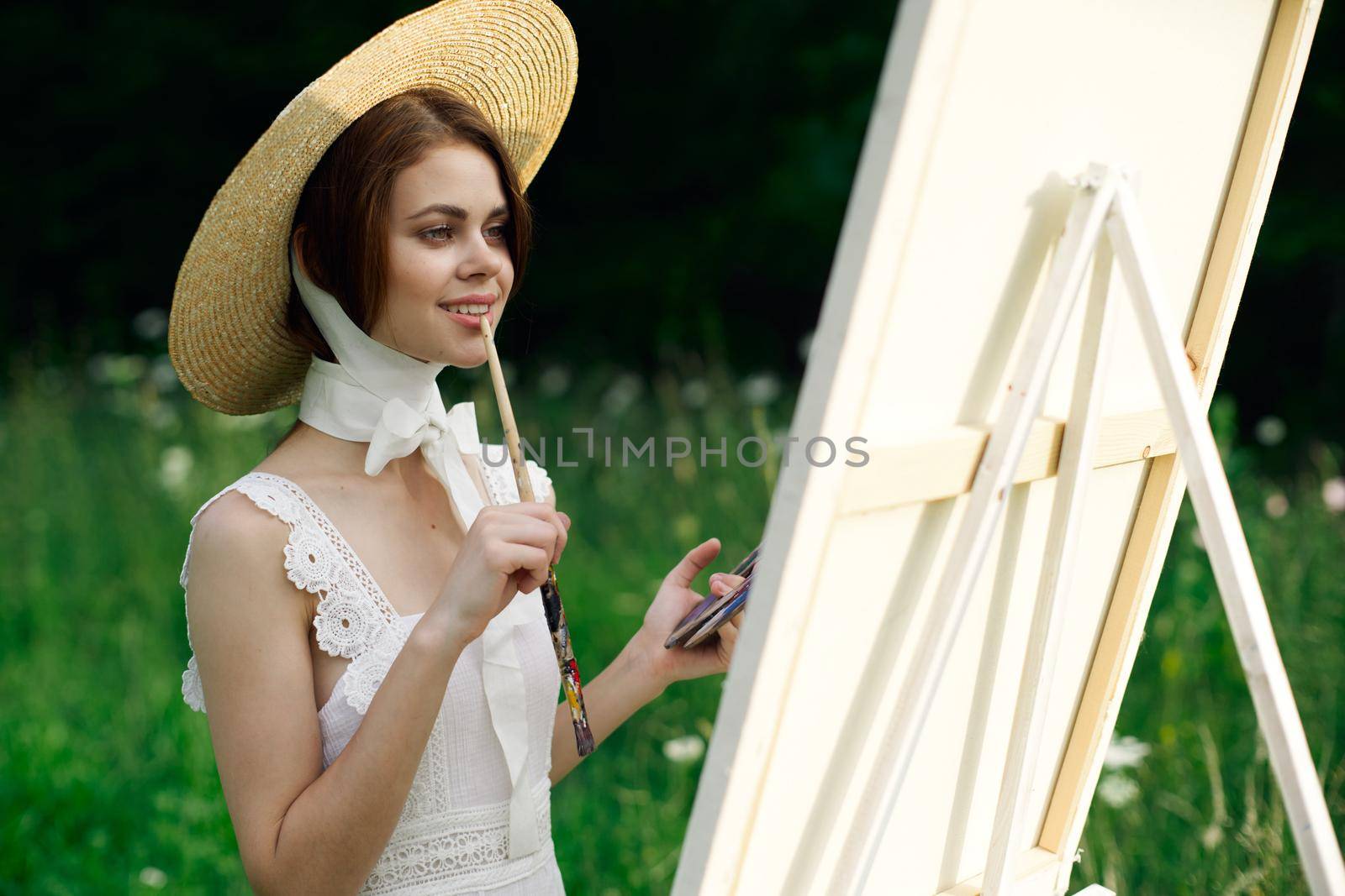 Woman in white dress artist easel painting nature landscape. High quality photo