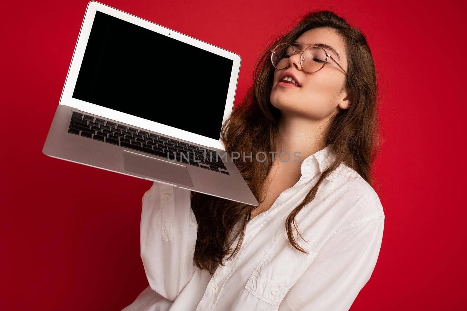 Close-up portrait of Beautiful smiling happy young woman holding computer laptop looking at netbook having fun wearing casual smart clothes isolated over wall background. free space
