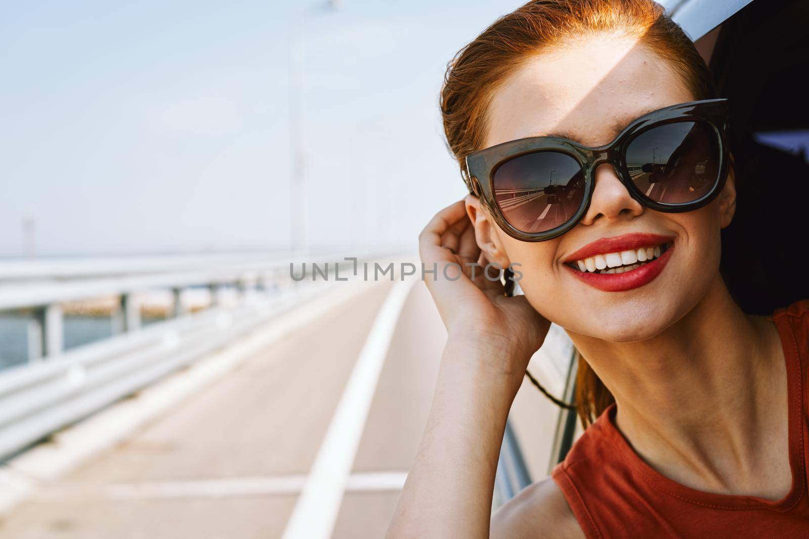 cheerful woman peeking out of the car window trip adventure lifestyle. High quality photo