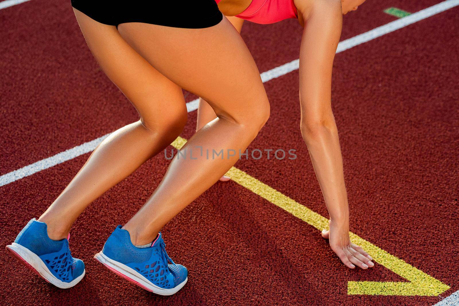 Close-up of woman's legs in blue sneakers on start before jogging. Red treadmill at the stadium