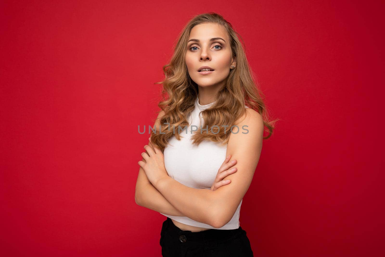 Portrait photo of young beautiful pretty self-confident assertive cool blonde woman with sincere emotions wearing stylish white top isolated over red background with free space.