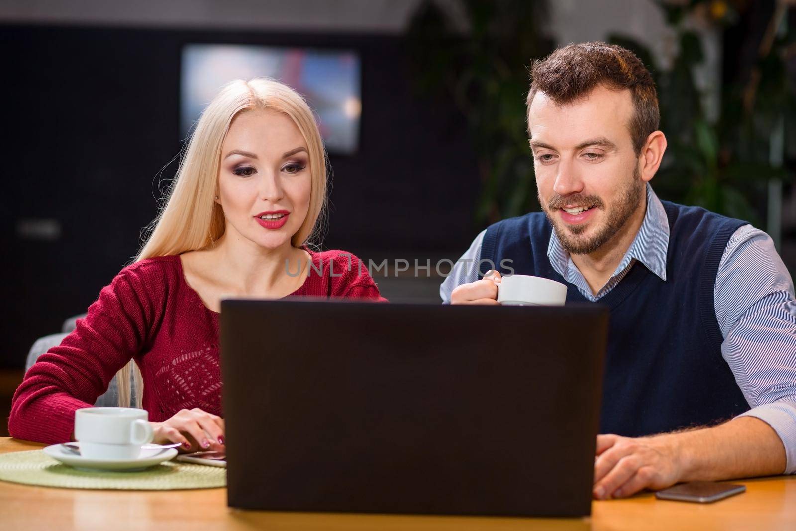 A woman and a man on a business lunch in a restaurant. discuss the project and look at the laptop screen