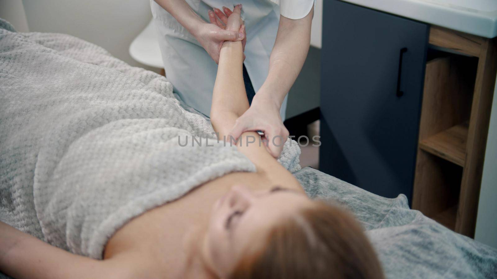 A therapist massaging hands of a woman in the cabinet - indoor