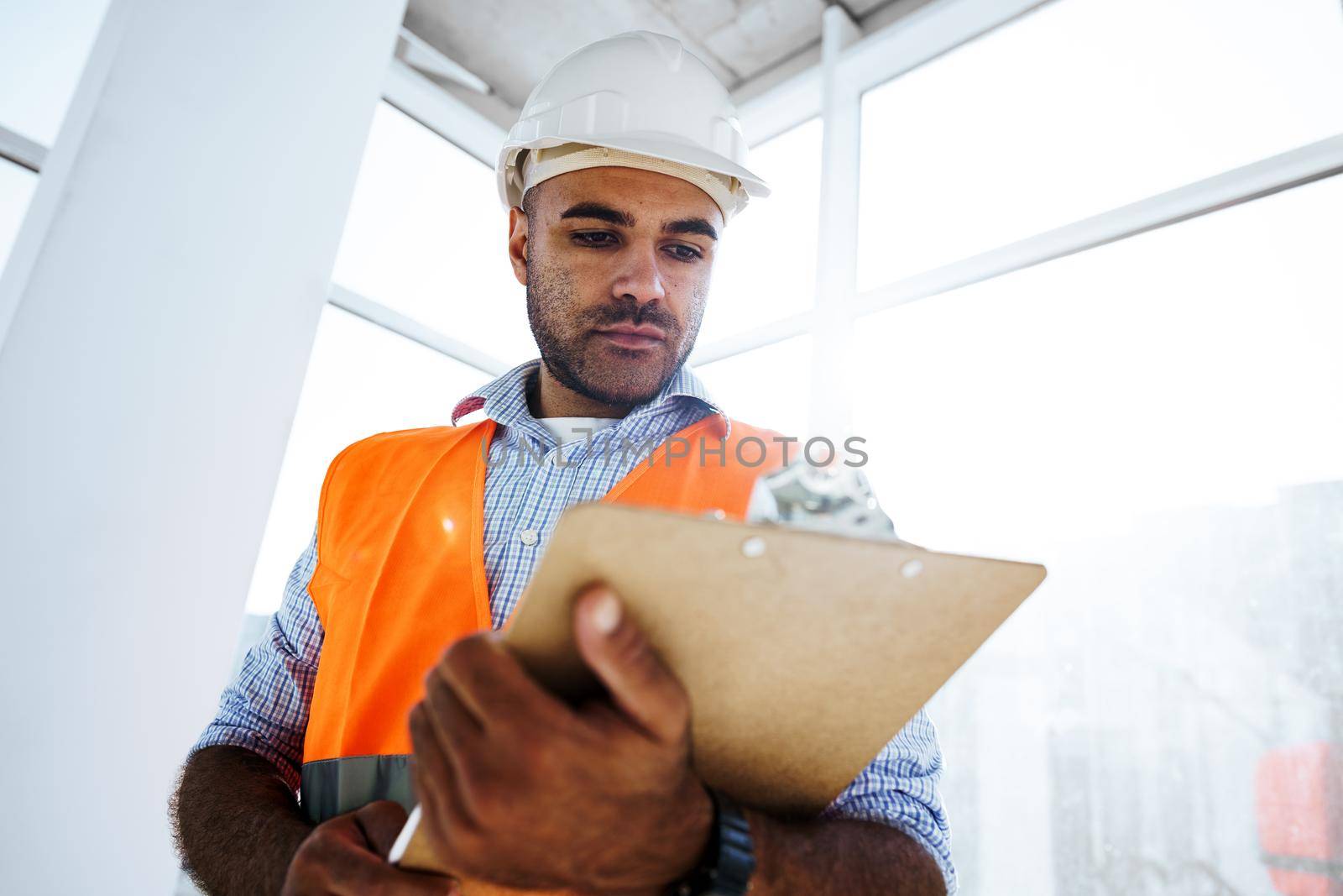 Foreman at work on construction site checking his notes on clipboard, close up