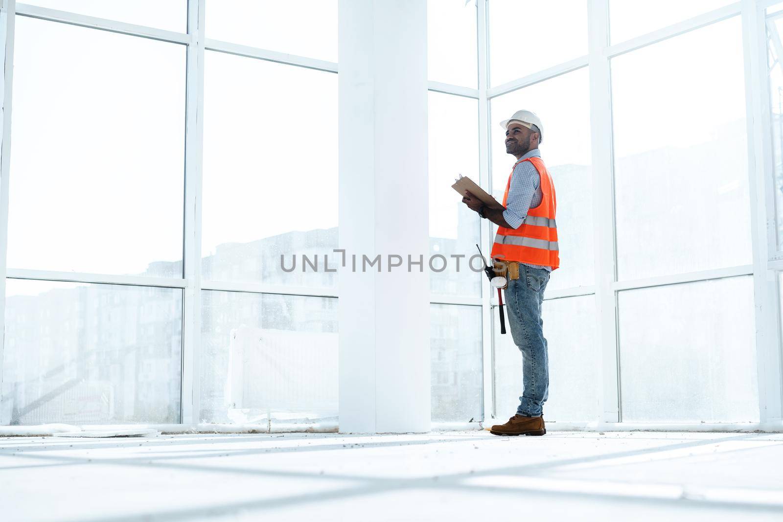 Foreman at work on construction site checking his notes on clipboard, close up
