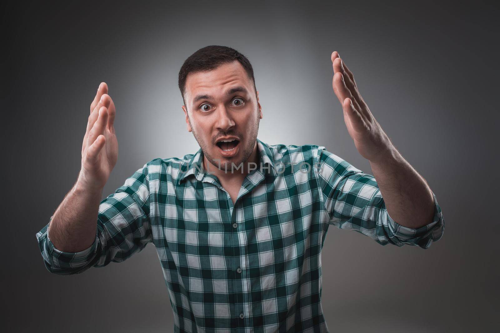 Portrait of man on gray background. Man showing different emotions. Man in green shirt in a cage