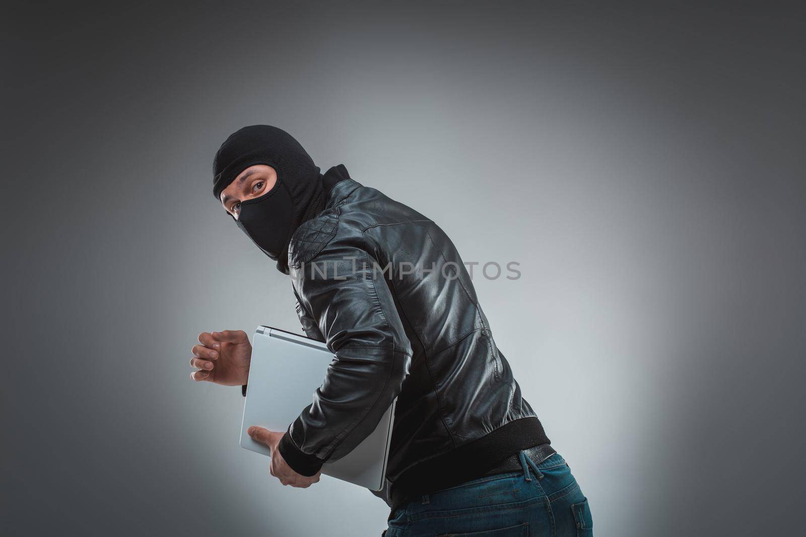 Thief stealing a laptop computer. Isolated on gray background by nazarovsergey