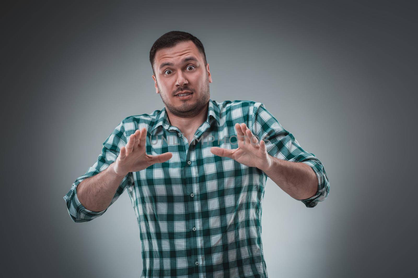 Handsome man with green shirt says stop. Isolated on gray background. Emotion concept