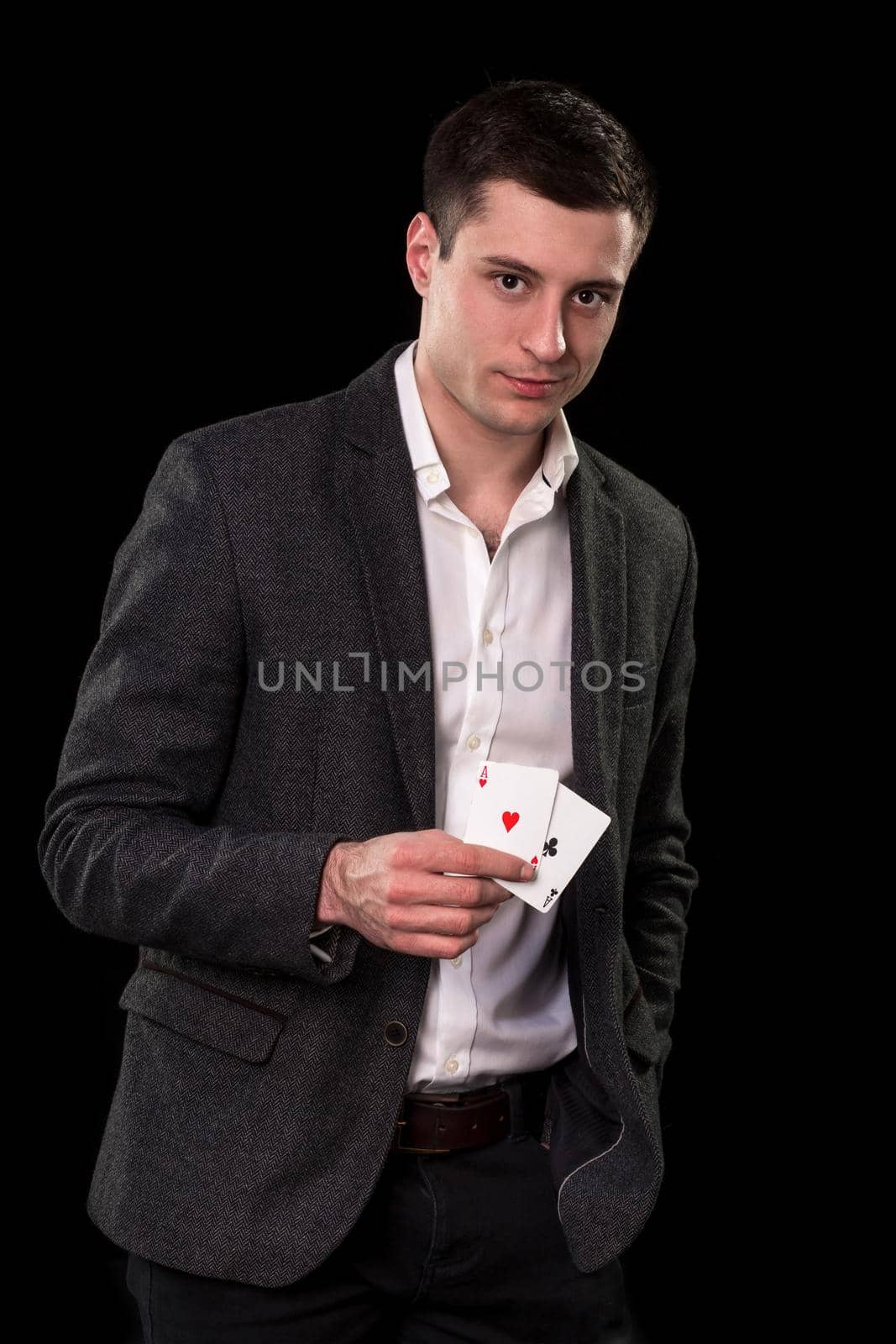 Young caucasian man in a dark suit and a white shirt holding two aces in his hand on black background. Gambling concept. Casino
