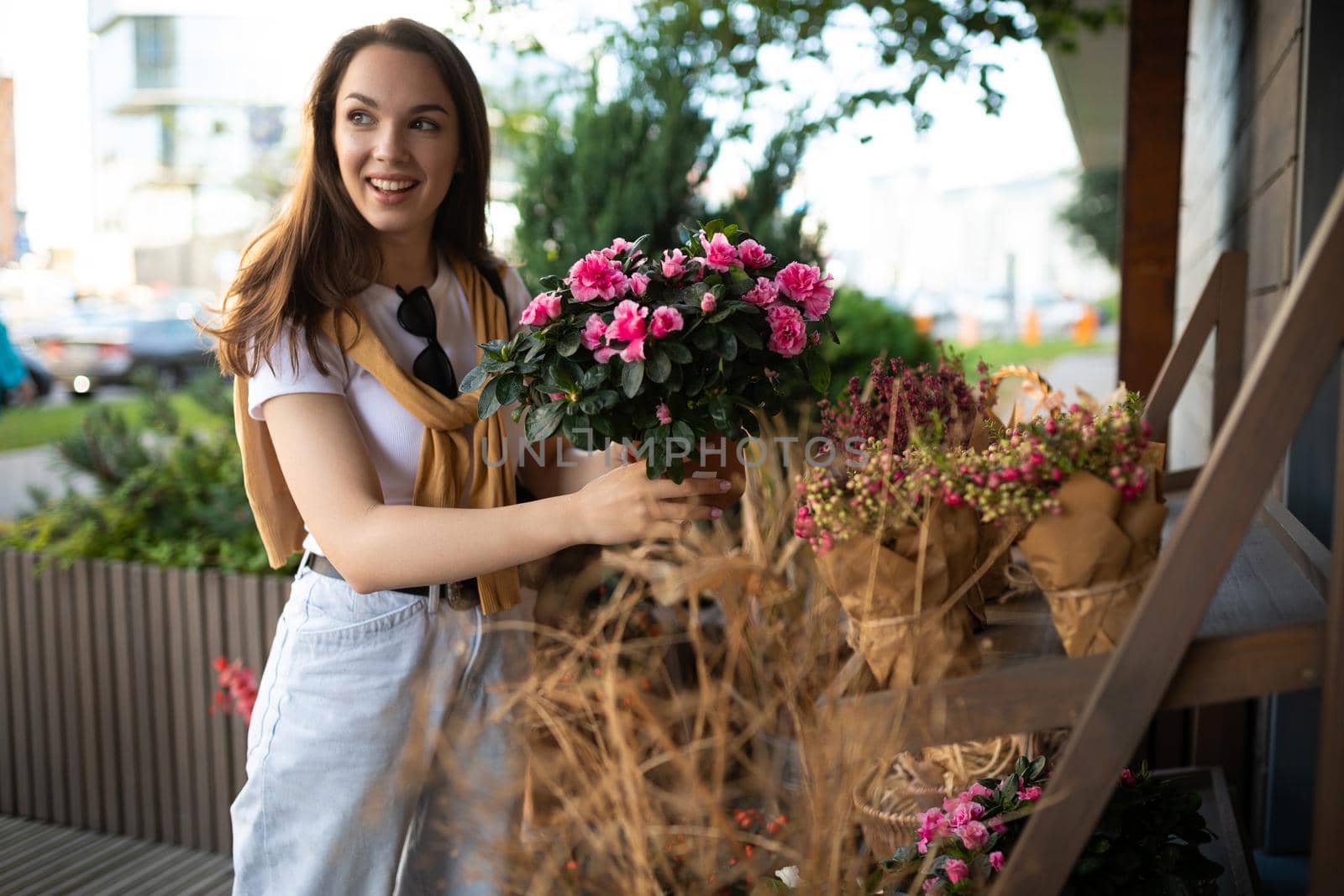 charming young woman buying flowers at garden summer shop.