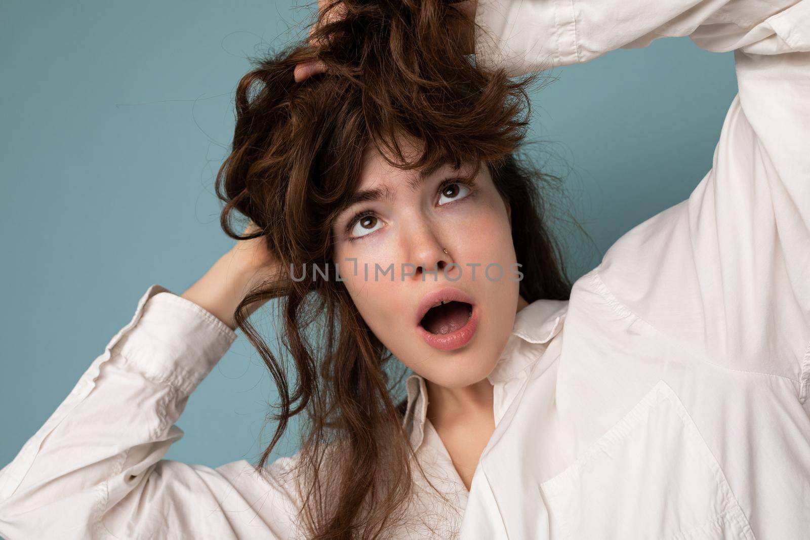 Closeup portrait of positive attractive crazy joyful funny young curly brunette woman isolated on blue background.