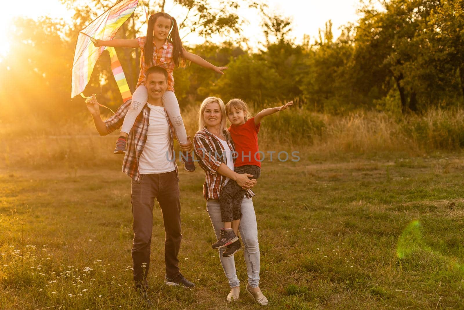 Happy family father of mother and daughters launch a kite on nature at sunset by Andelov13