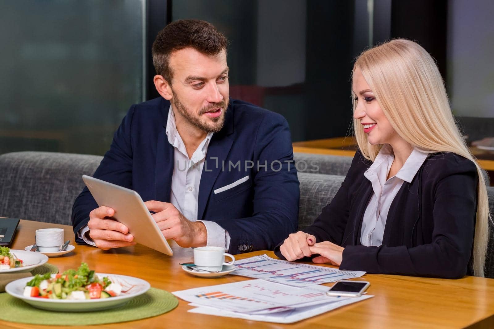 A woman and a man on a business lunch in a restaurant. exploring work on the tablet screen