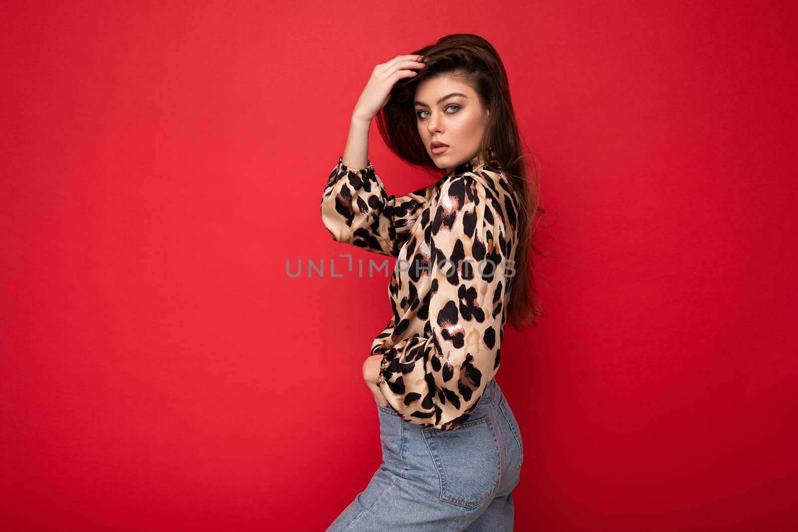 Close-up portrait of young nice-looking attractive lovely glamorous brunet woman wearing leopard blouse isolated on red color background with free space.