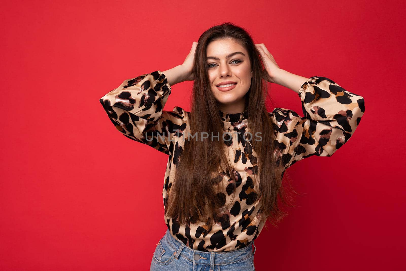 Photo of young happy smiling beautiful fashionable sexy brunette woman wearing stylish leopard blouse isolated on red background with empty space.