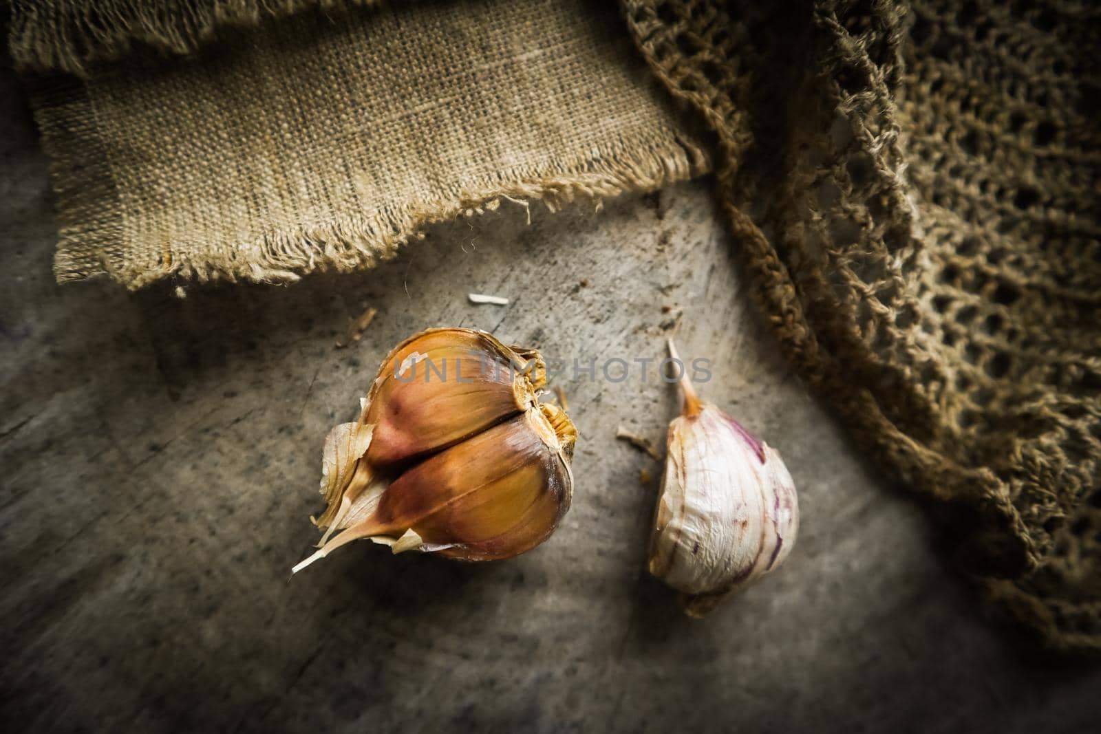 Garlic cloves and natural linen napkin on rustic wooden background