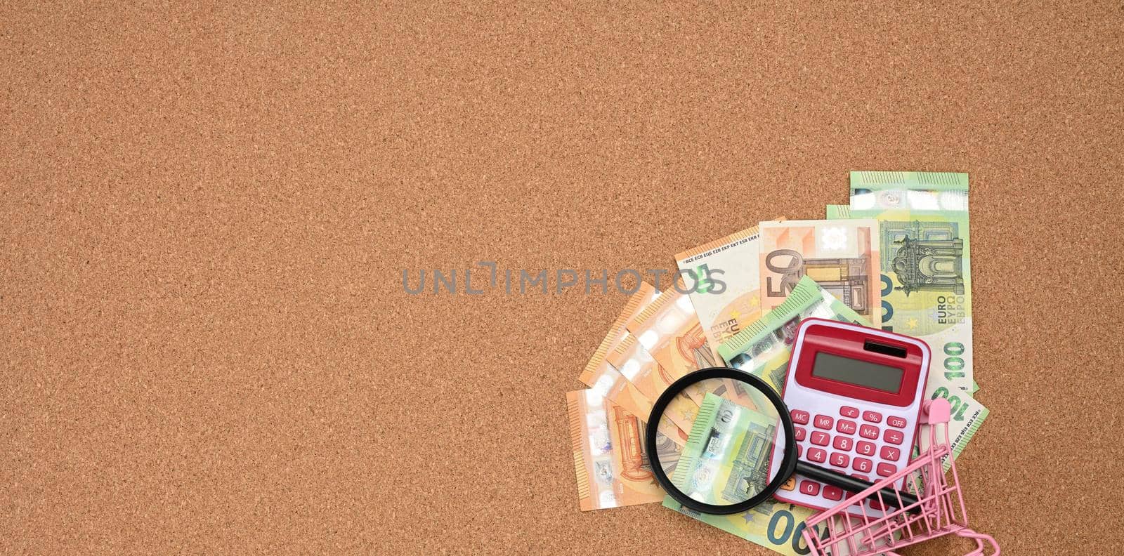 magnifier and paper euro bills on brown background. The concept of saving on purchases, increasing the price of goods