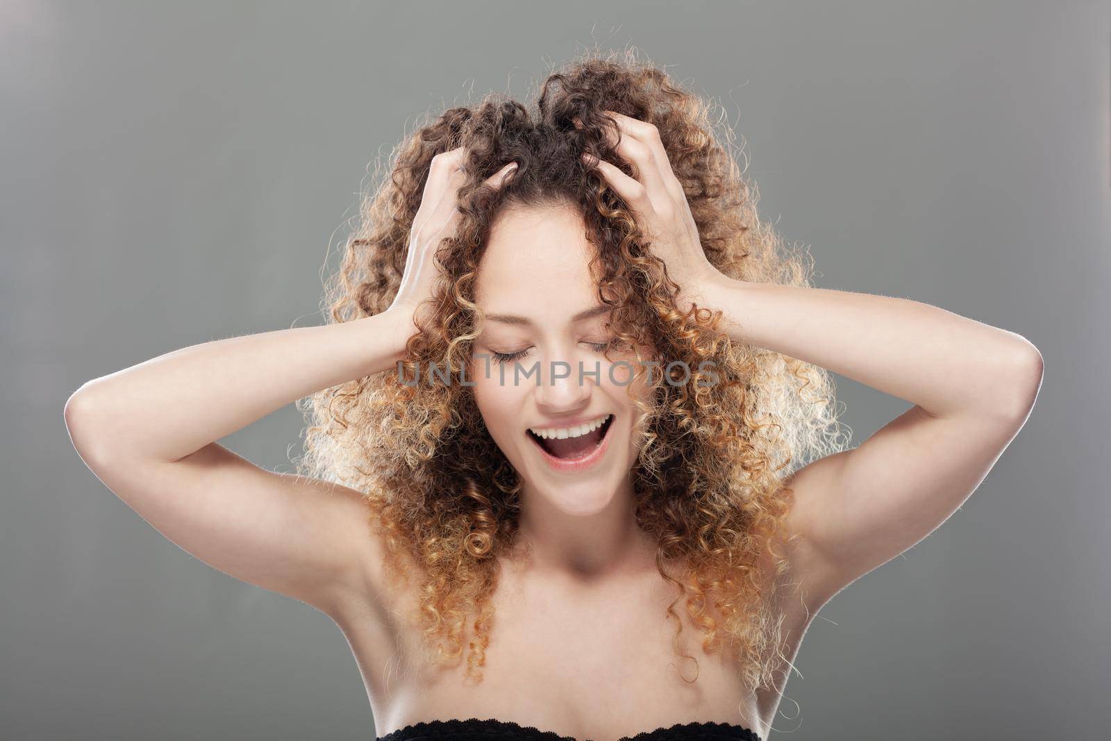 Beautiful brunette girl with long curly hair. Studio portrait. Happy smiling and singing face expression by kokimk