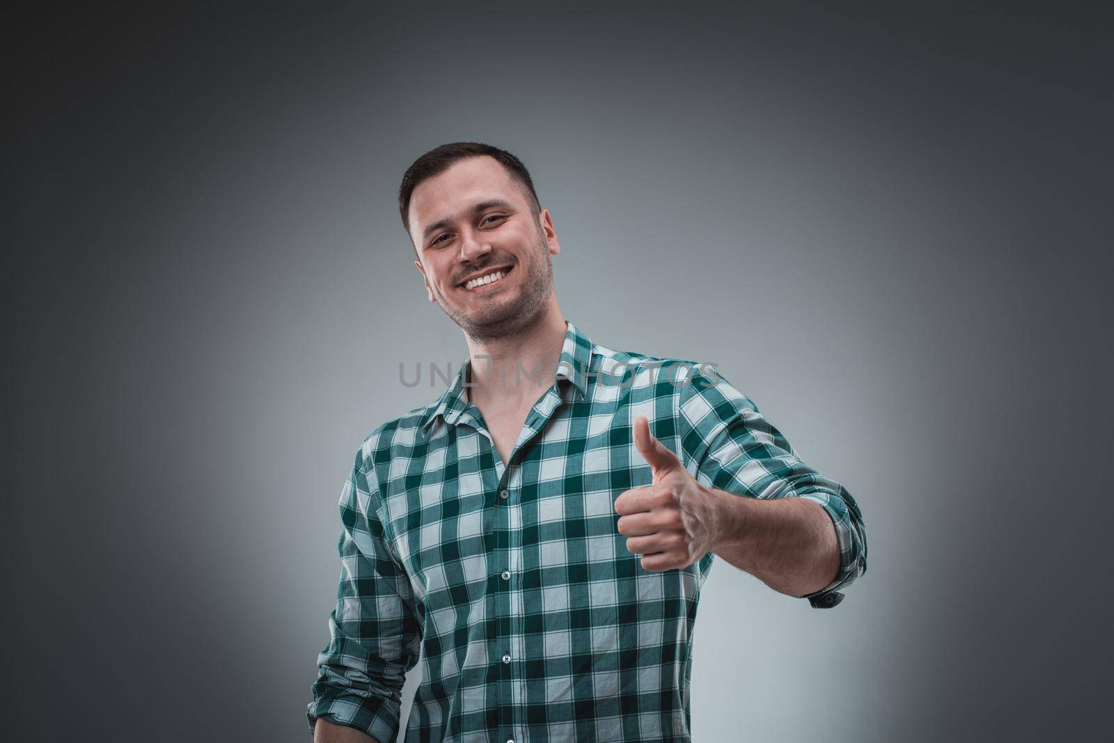 Portrait of man on gray background. Man showing different emotions. Happy screaming and smiling. Man in green shirt in a cage