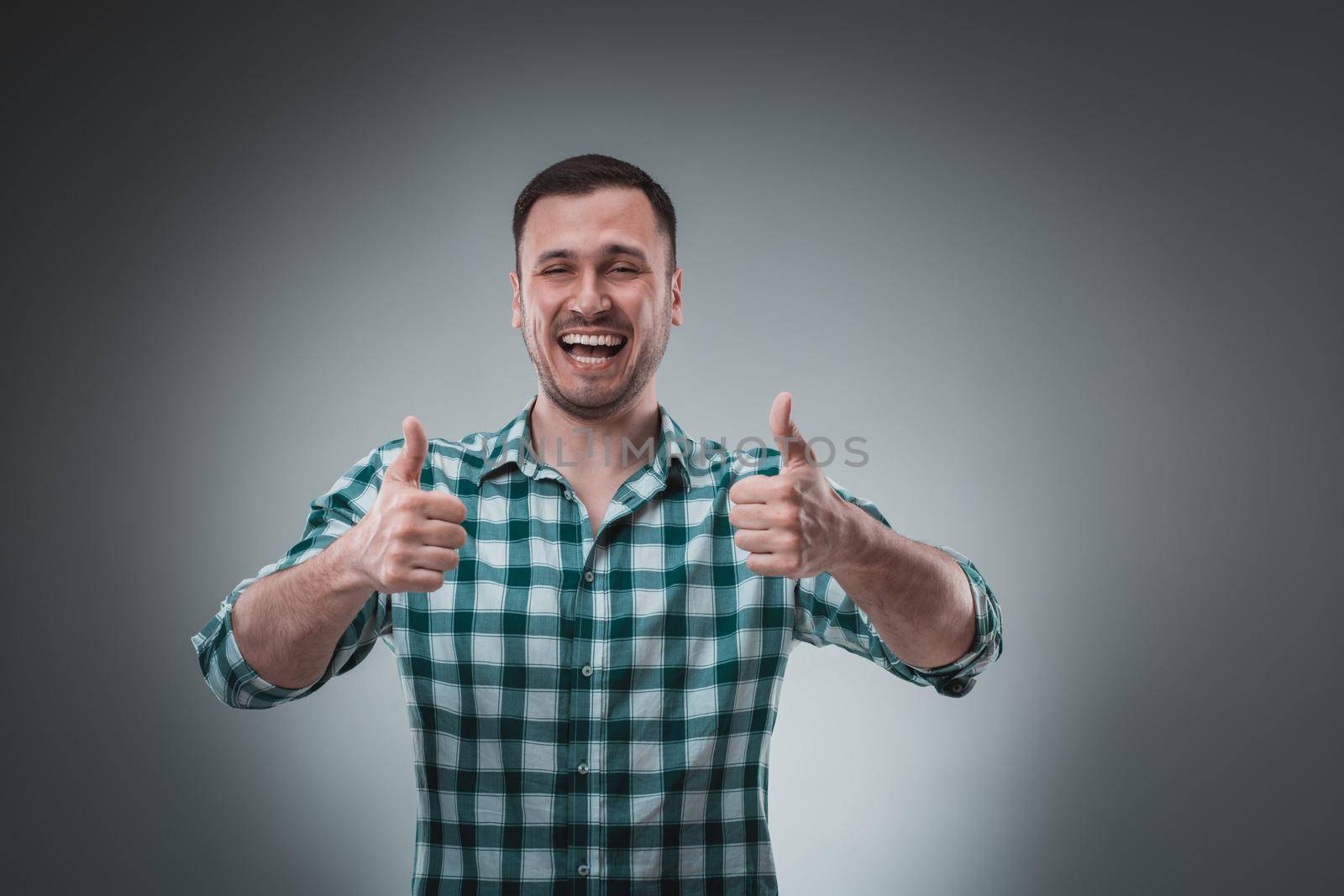 Portrait of man on gray background. Man showing different emotions. Happy screaming and smiling. Man in green shirt in a cage