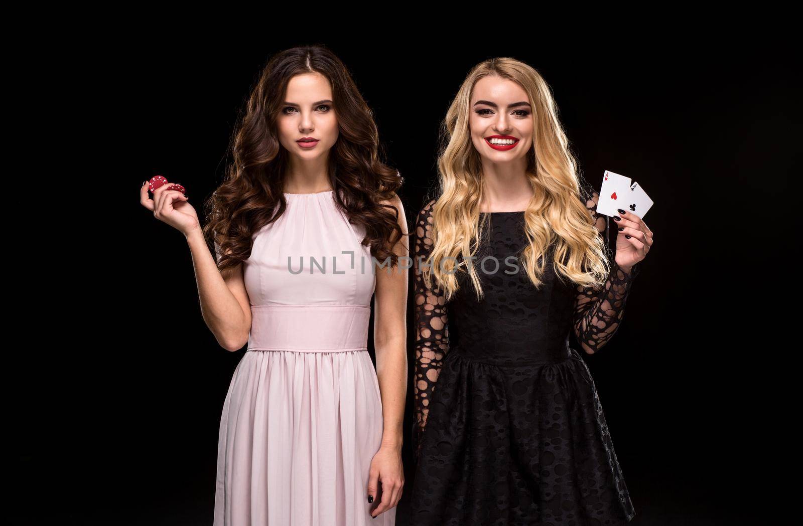 Two Sexy girls brunette and blonde, posing with chips in her hands, poker concept black background by nazarovsergey