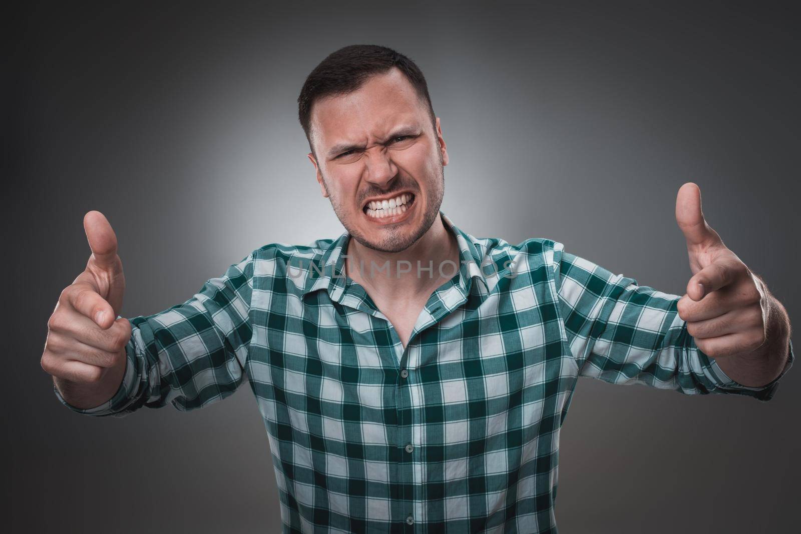 Portrait of excited man looking at the camera and points at you with a finger. Isolated on gray background. Emotion concept