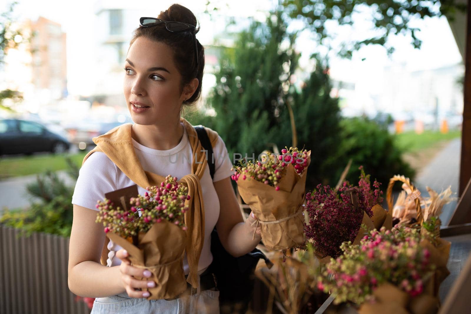 European woman chooses flowers as a gift in a street garden stall.