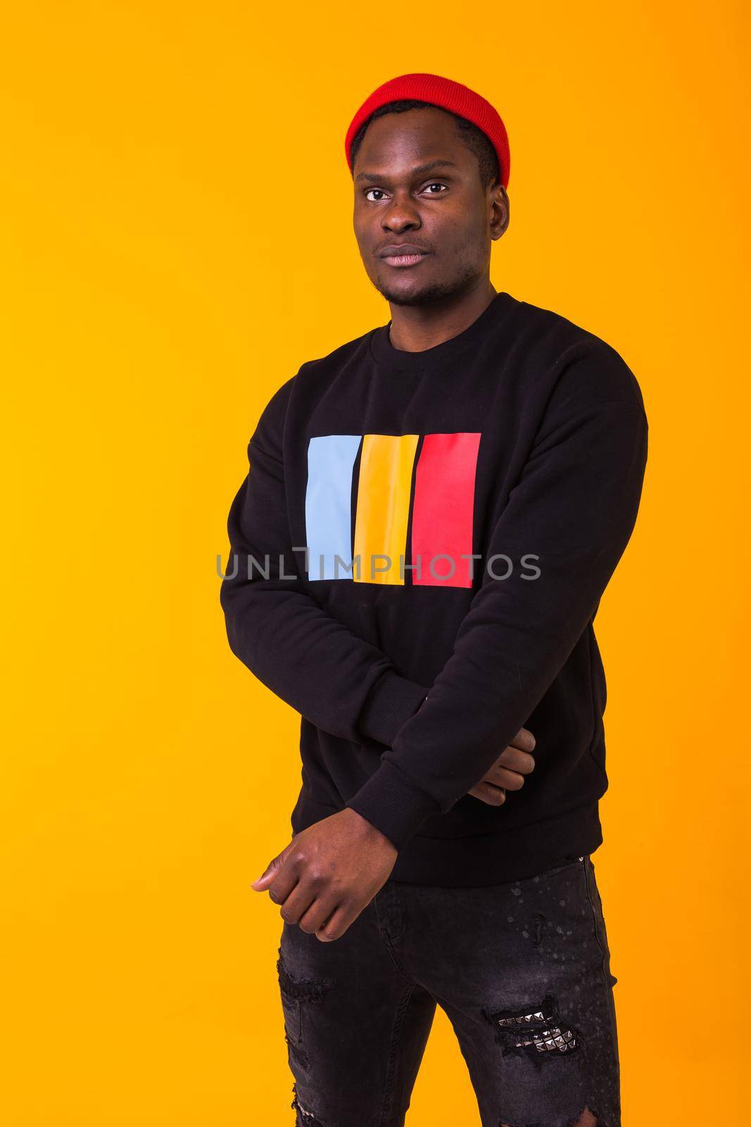 Youth street fashion concept - Portrait of confident sexy black man in stylish sweatshirt on yellow background. by Satura86