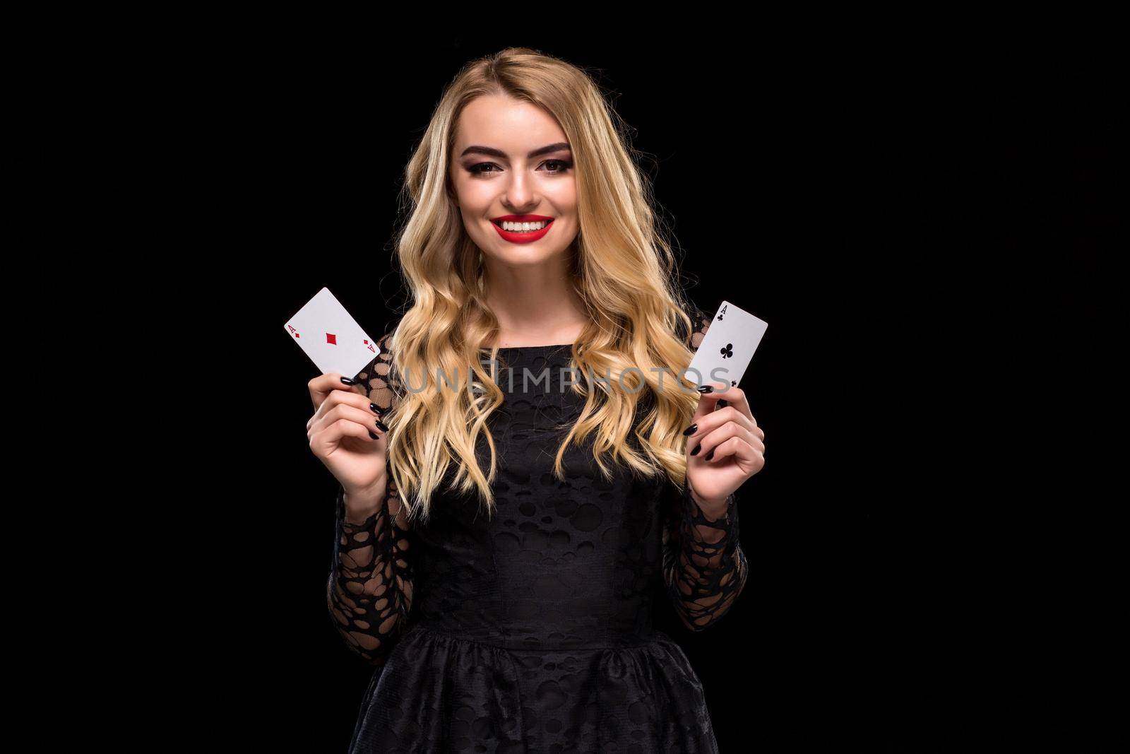 Beautiful young woman in black dress holding two ace of cards in her hand, isolated on black background. Poker. Casino. Roulette Blackjack Spin. Caucasian woman looking at camera