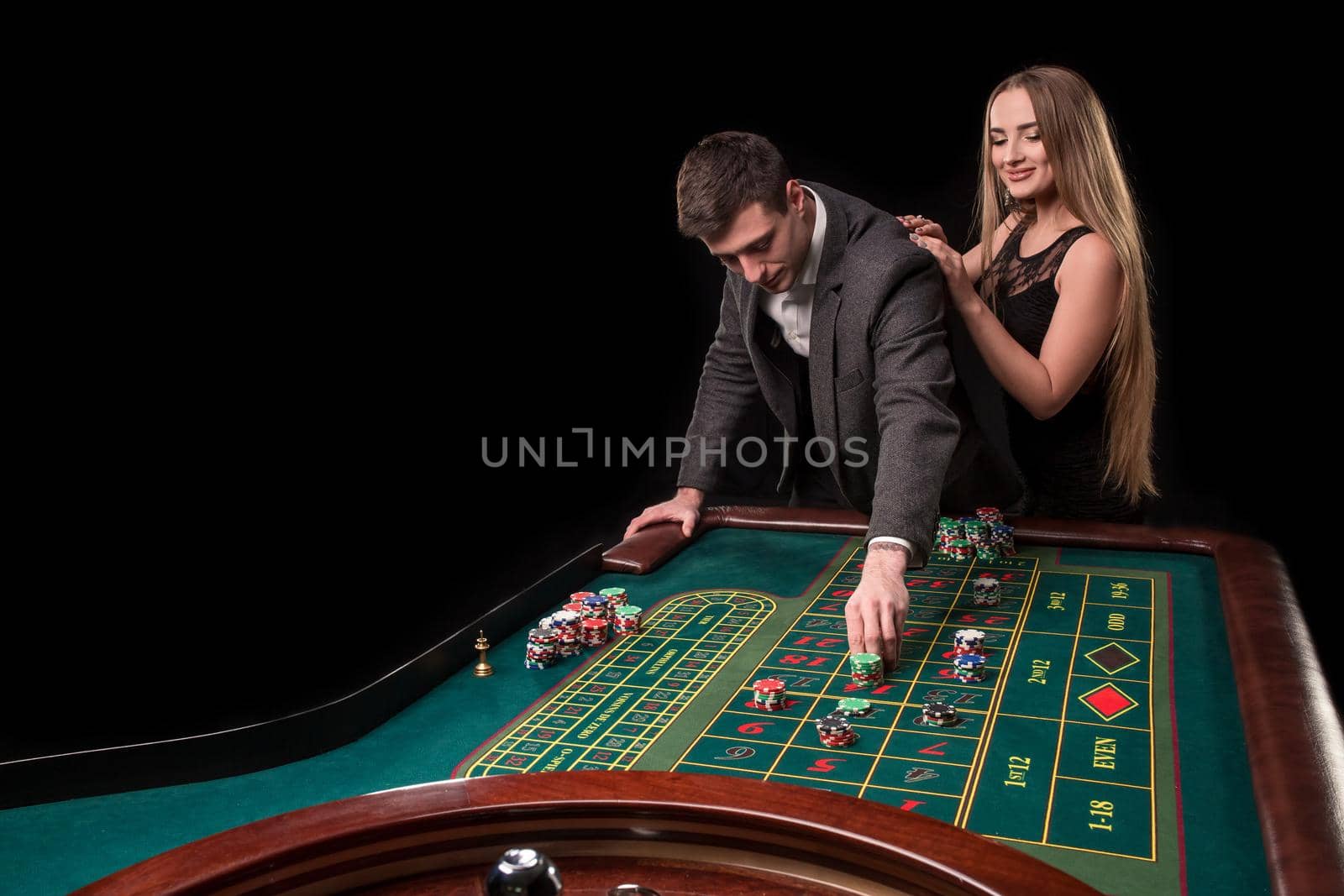 Elegant couple at the casino betting on the roulette, on a black background by nazarovsergey
